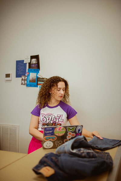 a young woman with a laptop, looking at denim jeans