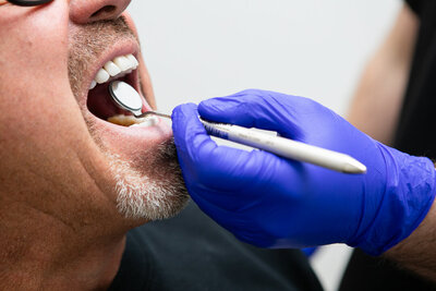 Prosthodontist inspecting a patient’s teeth and gum line for a gum contouring procedure at Peak Prosthodontics in Lethbridge, Alberta.