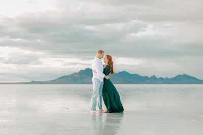 A man in a white shirt hugs a woman in a green dress at the Salt Flats