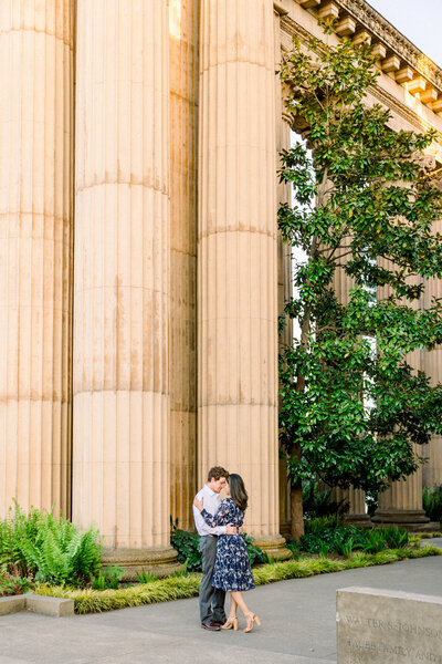 An engaged couple cuddles up at the Palace of Fine Arts in San Francisco for their engagement photos