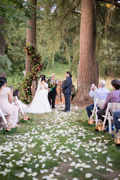 surrounded by roses and trees, couple says i do at evergreen meadows wedding venue in a garden captured by seattle videographer