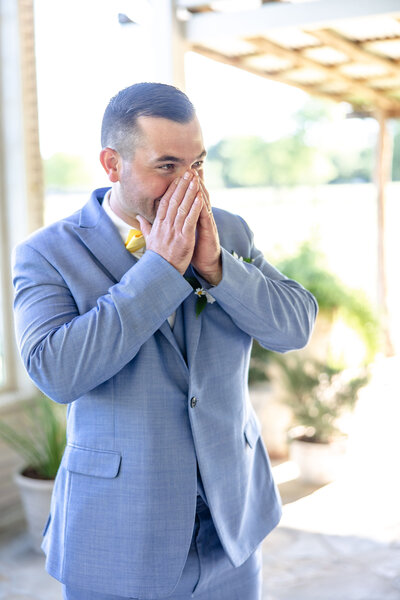 groom in blue suite grasps face in happy surprise at seeing bride on wedding day in New Braunfels