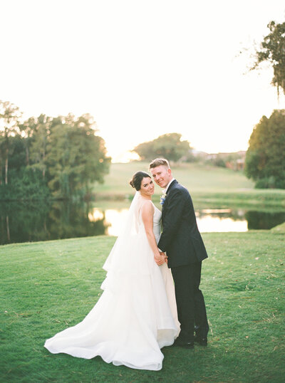 bride and groom holding hands lightly as they lean against a column on the Swan House