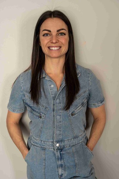 A woman in a tank top smiles warmly at the camera, embodying positivity and confidence. Jen Johnston Your True North.