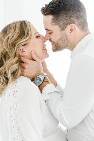 Parents-to-be smile while about to kiss during maternity photography session