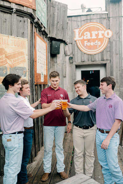 Group of college guys doing cheers with their beers outside
