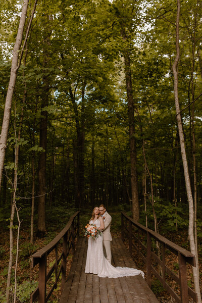 bride and groom posing on bridge