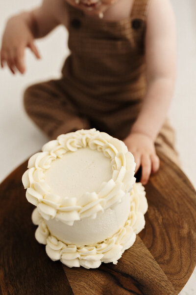 A little boy touching a first birthday cake smash cake during his photoshoot in christchurch