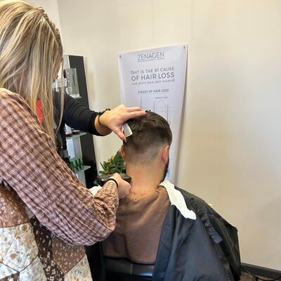 A hairstylist providing a precision haircut to a male client, showcasing the expert barbering services at 212 Salon, Spa, & Barbershop.