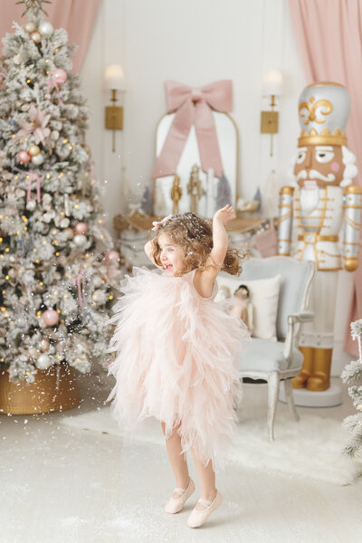 Girl in pink dress throwing snowflakes during nutcracker session in Phoenix