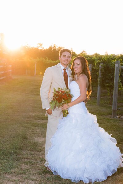 Bride and groom pose in vineyard