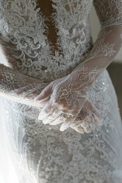 Detail of bride's hands with lace gloves.