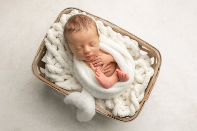 sleeping newborn baby with headband posed on creamy blanket