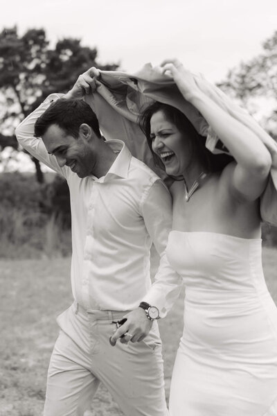 couple laughing and smiling at each other during their adventure session on a mountain top