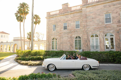 A bride and groom drive off into the sunset in downtown Sarasota in a vintage Rolls Royce vehicle as their Sarasota Florida photographer captures the moment!