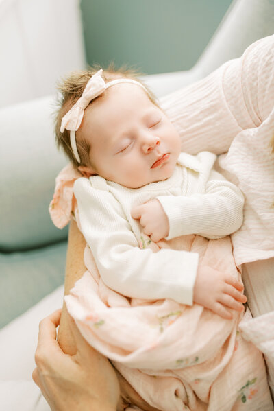 Newborn baby girl sleeps in mother's arms during her in-home newborn session  with Worth Capturing in Raleigh