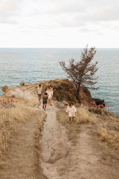 A family walks along a ridge above the beach in canterbury while being photographed by lucy jane photography
