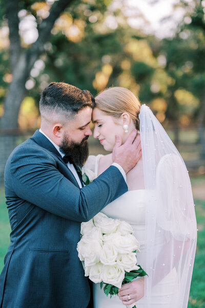 Groom holding bride's face while their foreheads touch