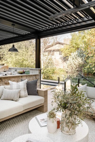 An outdoor patio with a covered sun-coast system and outdoor furnishings. 