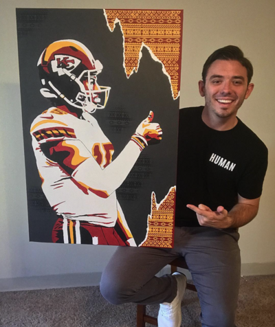 Alex Atkinson pointing at a canvas he painted of Kansas City Chief's quarterback