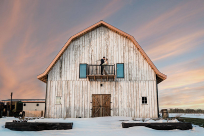 Bride and Groom standing on the balcony of Countryside Barn, a rustic, country Lethbridge, Alberta wedding venue, featured on the Brontë Bride Vendor Guide.