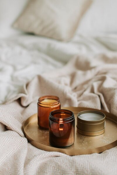 Lit candles arranged on a tray sit atop a bed, adding a serene and tranquil touch to the bedroom setting.