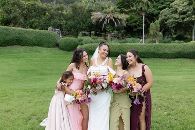 A newlywed smiling with their wedding party standing on either side 