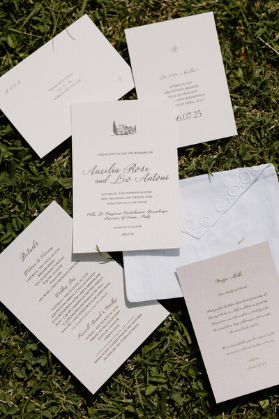Wedding invitations and save the dates laid out in the grass 