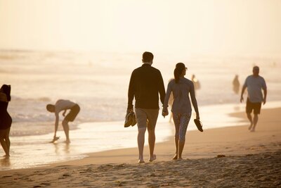 Couple walking on the beach with a tablet displaying Conflict Resolution Checklist for relationship coaching