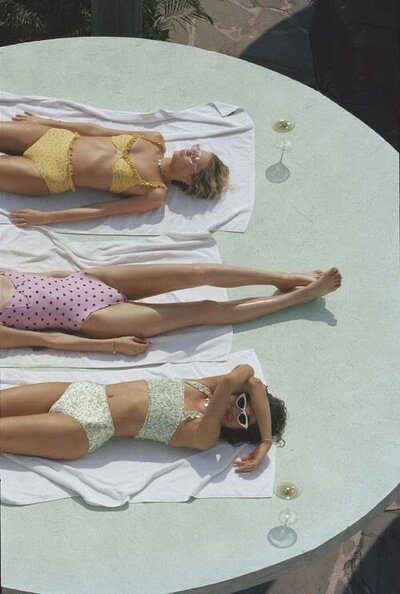 Image of bikinis on a sandy beach, suggesting relaxed and positive vibes.