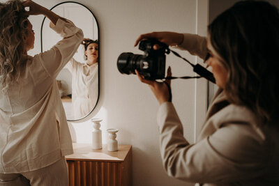 Photographer capturing a model as she plays with her hair in front of a mirror