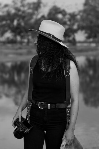 woman wearing a cowboy hat in a camera harness walking in a field