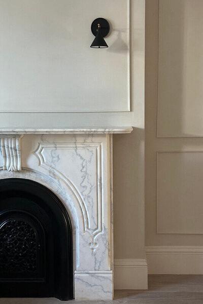 Brownstone interior designer in Boston created a modern look in a historic New England home, keeping the original marble fireplace and adding sleek black light fixtures.