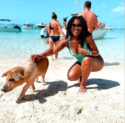 A woman swimming and petting one of Bahamas' famous swimming pigs while on an Aqua shores tour