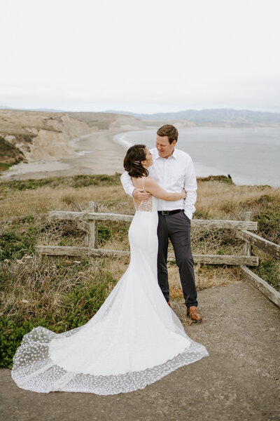 bride and groom embracing on cliffside