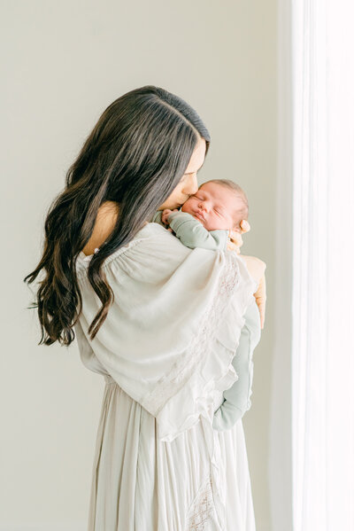 mother holding her baby and kissing him in the studio