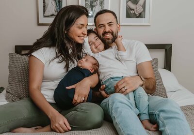 Family cuddled on master bed for newborn session in Chicago, IL
