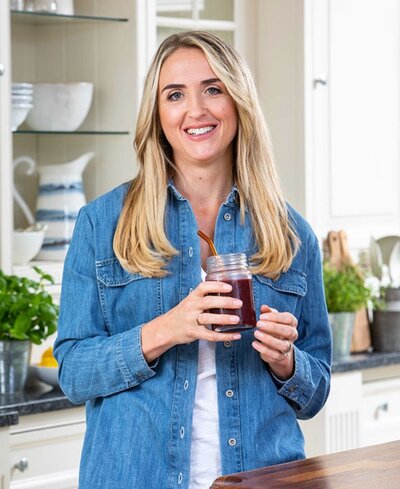 Charlotte Grand, nutritionist, personal trainer and founder of The Menopause Kitchen, smiling in her kitchen holding a smoothie jar