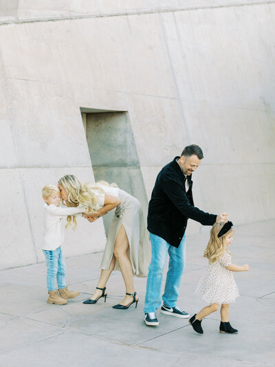 mother kissing son's head while father walks with daughter