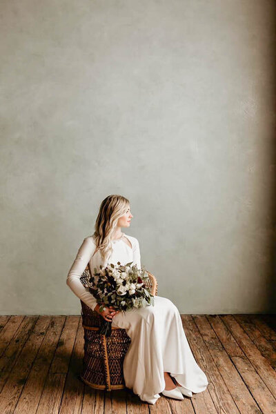 Bride looking out window holding her floral bouquet.