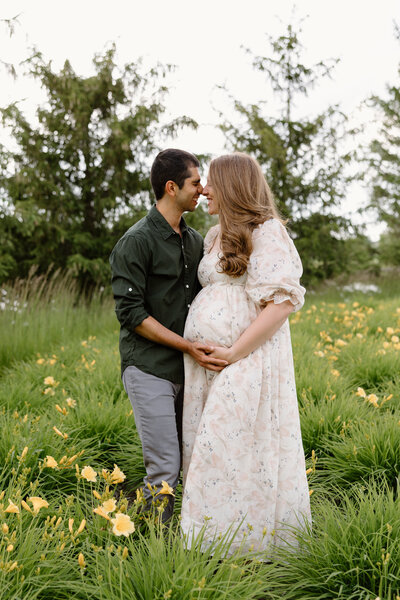 Expecting couple standing nose to nose in a field of daffodils during Indianapolis maternity photos