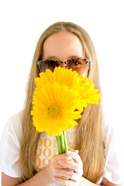 Tween girl wearing sunglasses with yellow daisies in her face. Family Photographer Newport Beach CA.