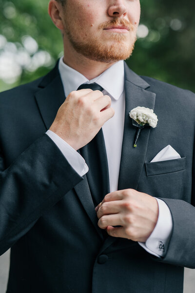 Groom straightening his tie on a wedding day at Summerfield Farms in Greensboro NC