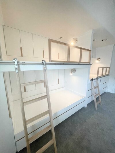 Frisco luxury home transformations featuring a children's bedroom with multiple beds, white decoration, and elegant touches for a sophisticated and stylish look.