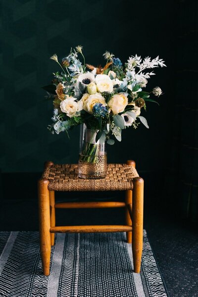 A bridal bouquet sits atop a chair and represents an example of wedding flowers designed by Flowers and Thyme.