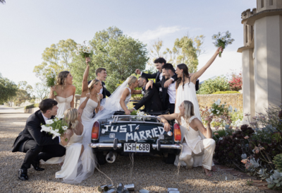 Wedding Party all sitting in and around a car celebrating after the wedding ceremony 