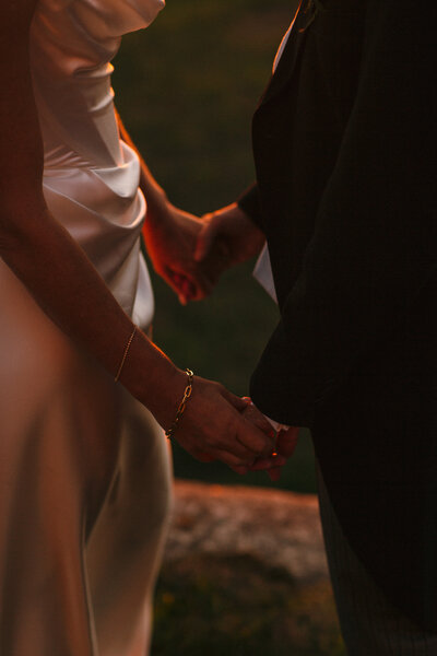 Golden hour hands of newlyweds catch the last of the sunset rays