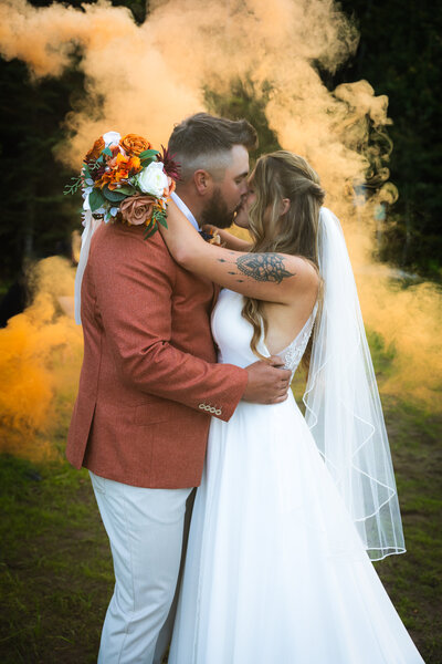 Photo des mariés en automne avec bombe de fumée orange
