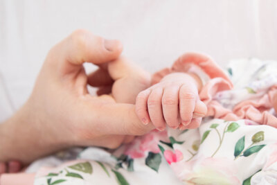 Color Photo of Newborn holding finger of parent