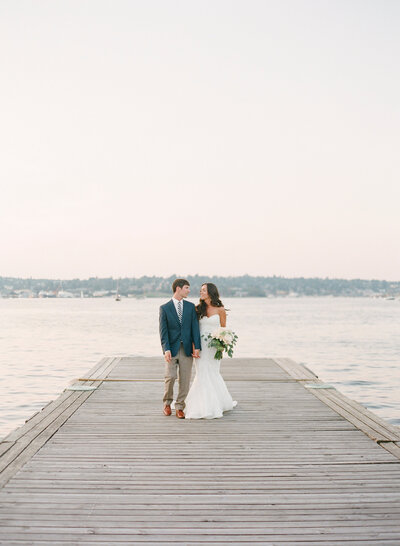 bride and groom walking on dock on lake union